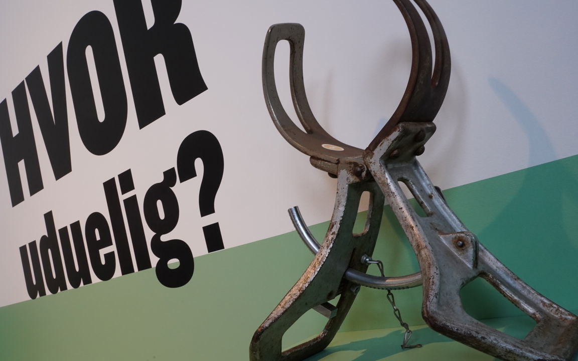 Foto af hovedmåler og skrift på væg: "Hvor uduelig?"