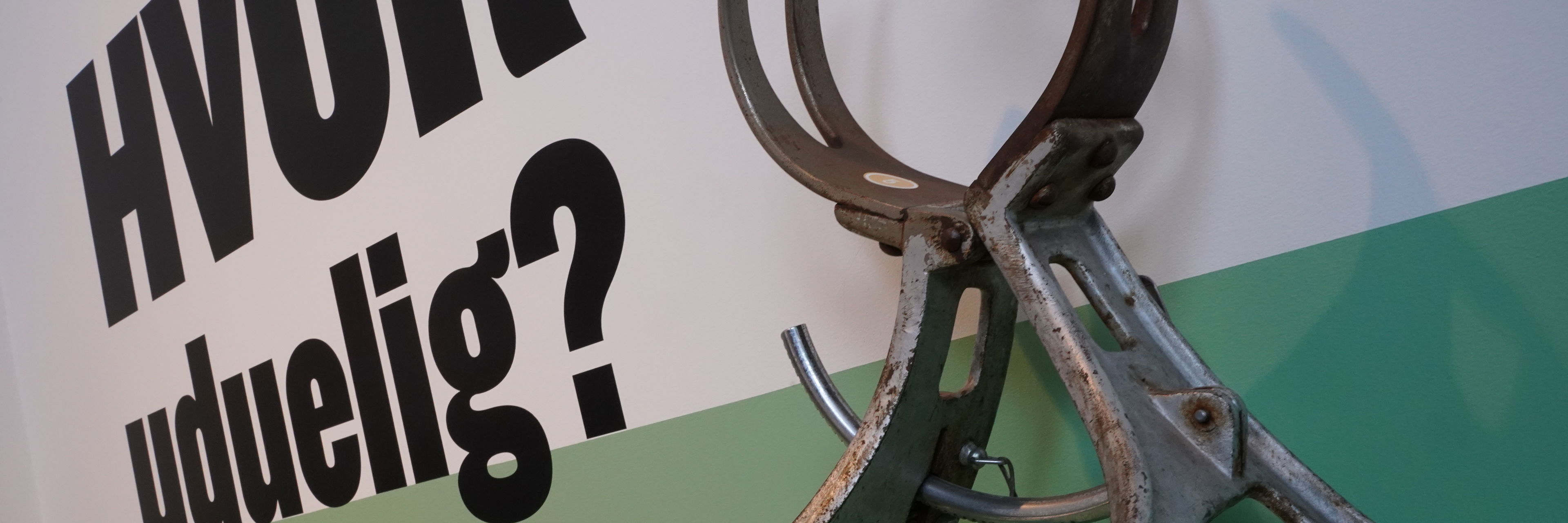 Foto af hovedmåler og skrift på væg: "Hvor uduelig?"